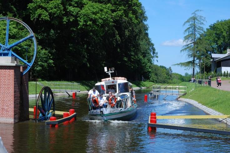 Statek BURSZTYNEK , pochylony na prawą burtę przepływa koło kół kierunkowych. Górna stacja Buczyniec