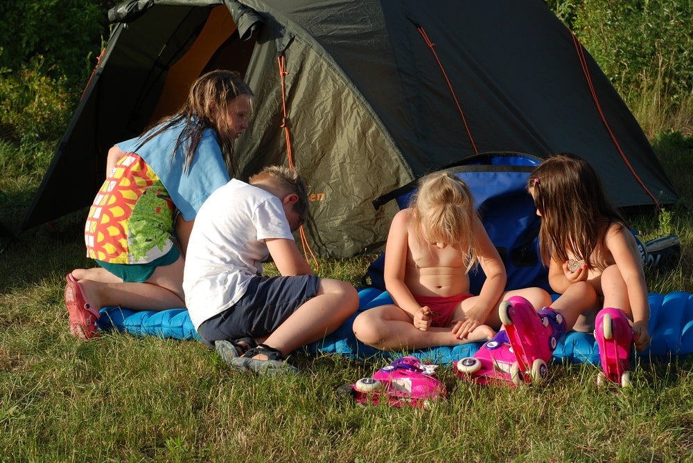 Dzieci siedzące przed namiotem.