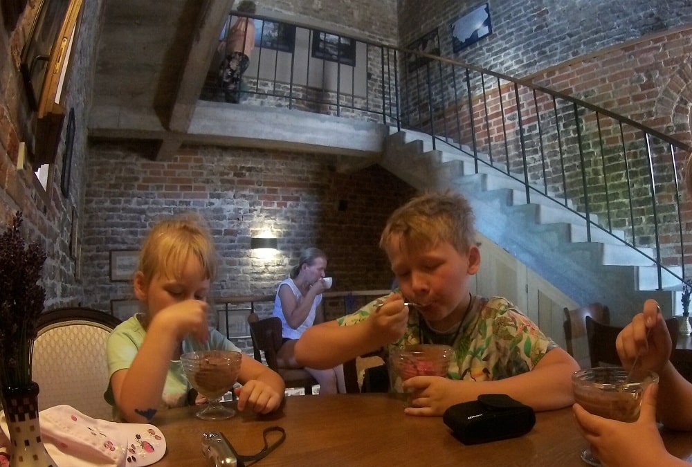 Piętro kawiarni w Wieży Wodnej. Dzieci jedzą lody w tle kobieta pije kawę.