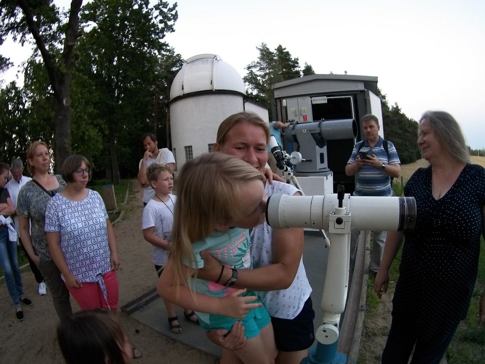 Mama z córką obserwują okolice przez lunetę.