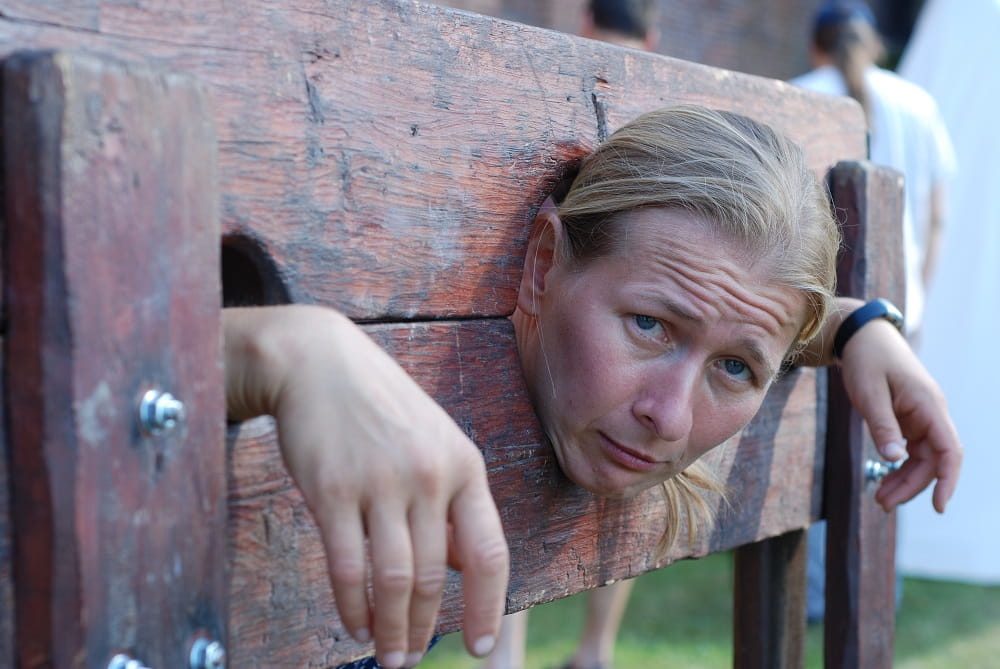 Zakuta w dybach. Blądynka. Mina smutna.