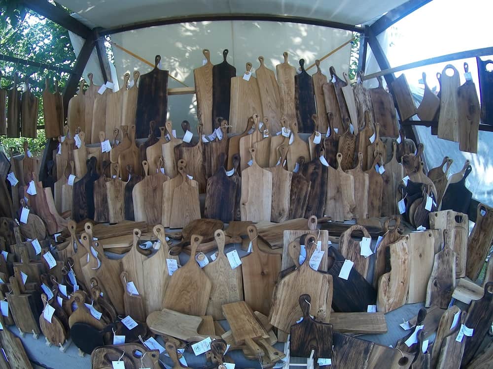 Deski do krojenie wystawione na straganie. Deski te wykonane są z różnego rodzaju drewna i różnych kształtów, ustawione jedna przy drugiej.