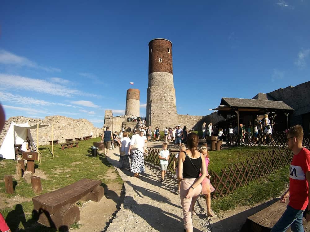 wnętrze ruin. W tle dwie okrągłe wierze zamku. Na tej dalszej powiewa biało-czerwona falag