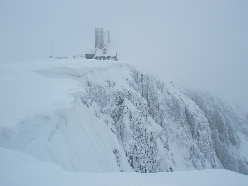 Ośnieżony krajobraz. na pierwszym planie strome ściany śnieżnych kotłów, miejsca przytulnego wspinaczom. Na skraju kotłów budynek z wieżą, dawniej to było schronisko