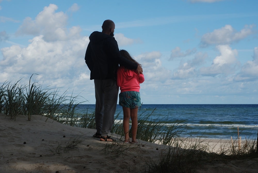 Ojciec z córką zapatrzeni w morze o poranku.