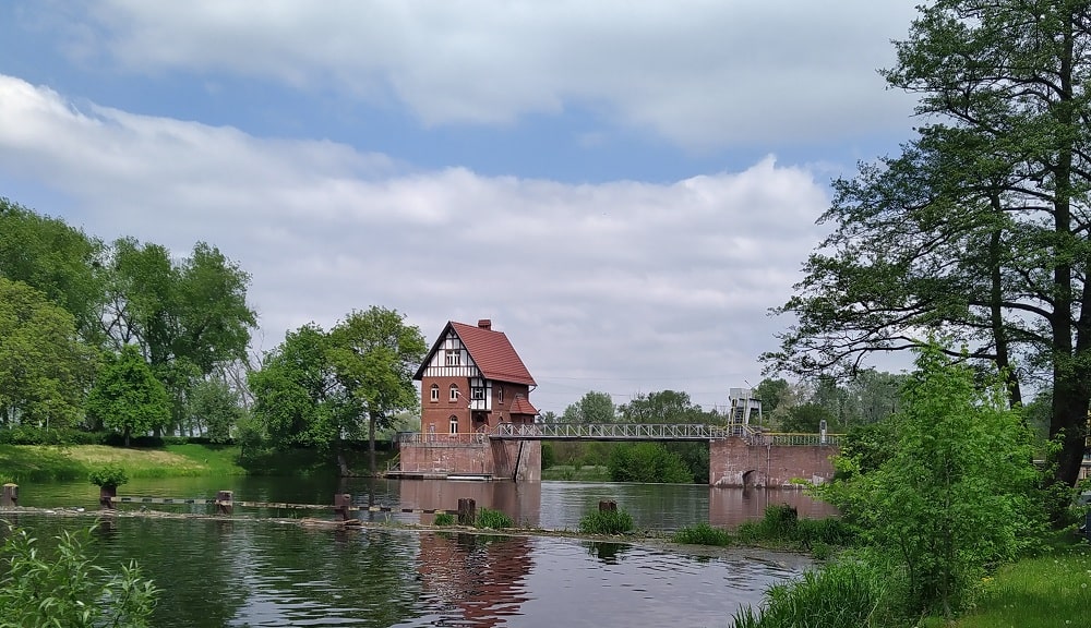 Jaz walcowy w Czersku Polskim. Po lewej stronie na wyspie budynek na trzy piętra wysoko z dachem dwuspadowym i murem pruskim na ostatniej kondygnacji. Nad wodą metalowa konstrukcja mostu łącząca dwa przyczółki ceglane (może licowane cegłą)