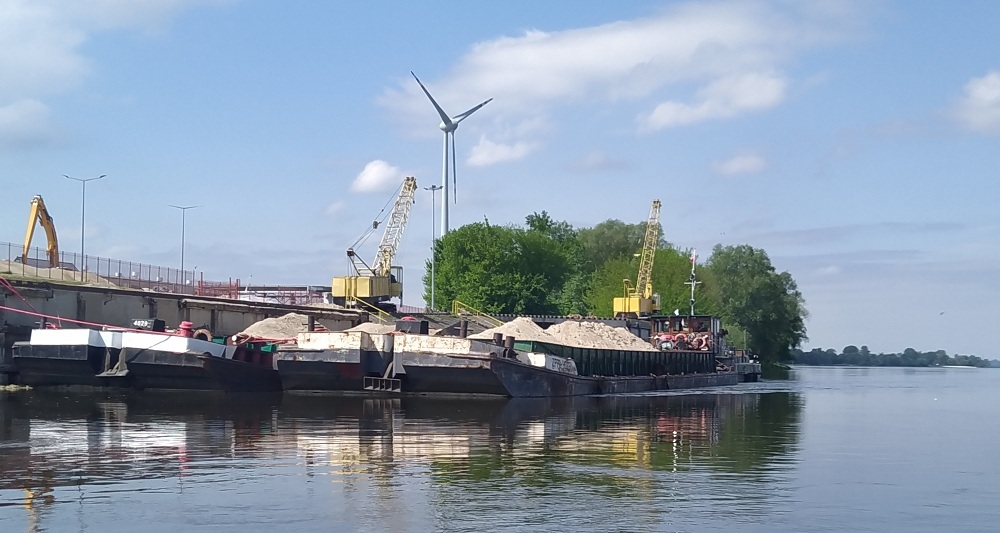 Barki z piaskiem cumują przy umocnionym brzegu gdzieś przed Bydgoszczą jeszcze przed Solcem Kujawskim. Na każdej barce mała żółta koparka wybierająca piach z Wisły