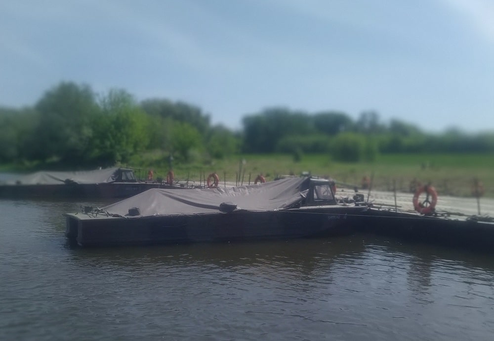 Wojskowa przeprawa pontonowa. dwie motorówki i pontony do przeprawy.